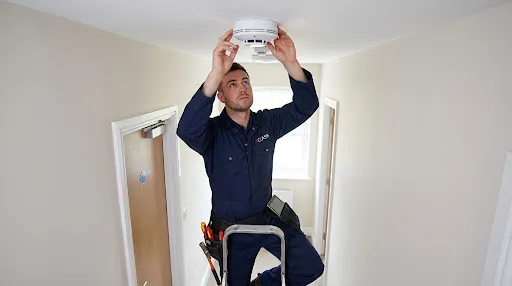 Fire alarm engineer servicing a smoke detector in an HMO property
